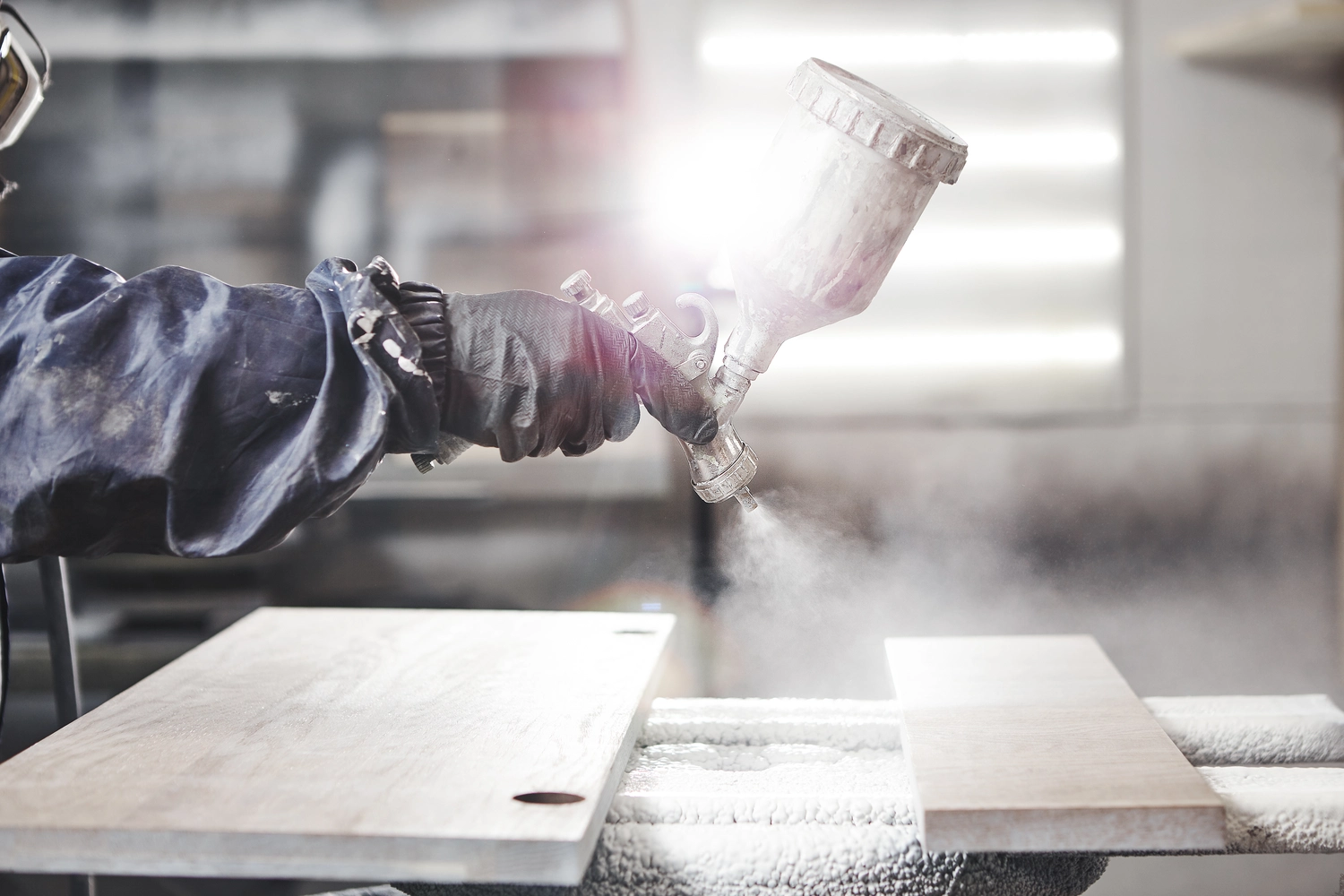 Lackiertechnik John - Fahrzeug Lackierer - Holzbeizen mit einer weißen Spritzpistole. Auftragen eines Flammschutzmittels zur Gewährleistung des Brandschutzes mit einem Airless-Spritzgerät.